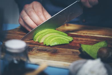 Avocado wird auf einem Holzbrett in Scheiben geschnitten