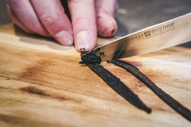 Vanilleschote auskratzen mit Messer auf Holzbrett
