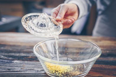 Gepresster Zitronensaft wird in eine Glasschale gekippt