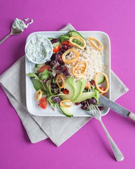 Ein Salat, angerichtet auf einem weißen Teller auf pinkem Hintergrund