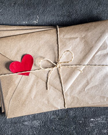 Paket Briefumschläge mit Herz auf dunklem Steinuntergrund
