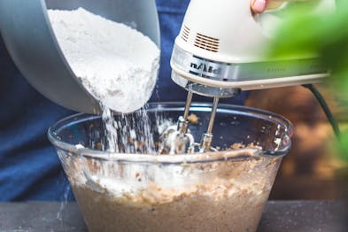Mehl wird unter ständigem Mixen in die Glasschüssel gegeben.