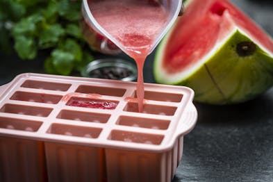 Eine rosa-farbene Eisform wird mit pürierter Wassermelone gefüllt.
