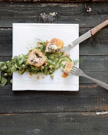 Cordon Bleu mit Wasabinüssen und Schmorgurke auf weißem Teller.