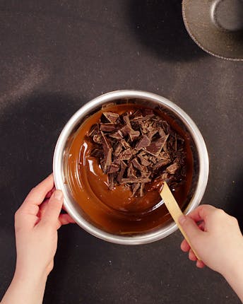 In einer Metallschüssel wird ein Teil fester Schokolade zum Impfen unter einen Teil geschmolzener Schokolade gerührt