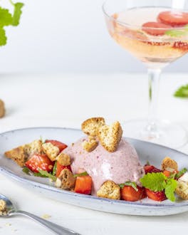 Erdbeer-Eis auf Teller mit frischen Erdbeeren, Melisse und zerbröselten Cantuccini