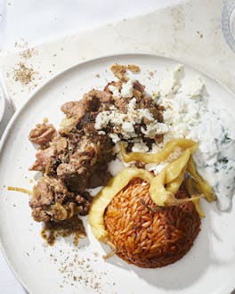 Kritharaki-Nudeln neben Gyros und Joghurtsauce auf einem weißen Teller