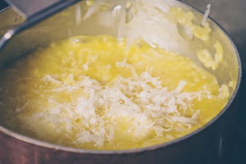 Parmesan wird über Risotto im Topf gerieben