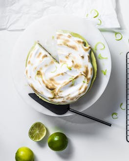 Angeschnittener Key Lime Pie mit flambierter Baiserhaube vor hellem Hintergrund
