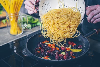 Spaghetti werden zu anderen Zutaten in der Pfanne gegeben