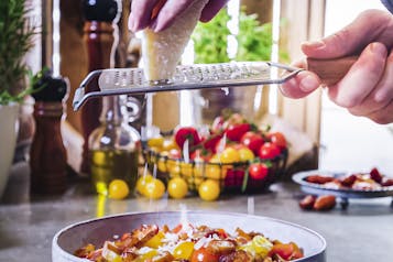 Pecorino mit Reibe über bunte Tomaten reiben