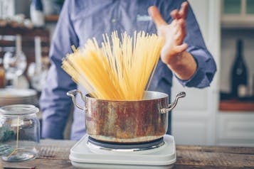Spaghetti stehen aufgefächert in einem Kochtopf auf einer Kochplatte
