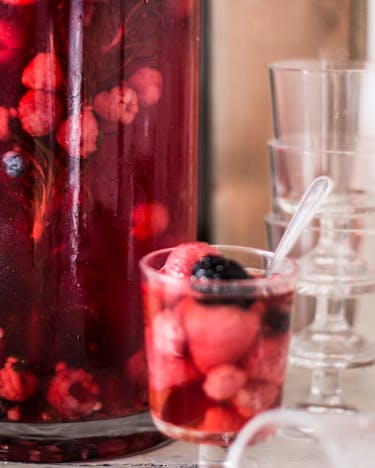 Erfrischender Drink mit roten Beeren in einem Glas mit Löffel.