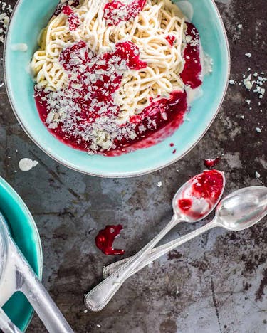 Klassisches Spaghettieis mit Sahne, Erdbeersauce und weißen Schokoraspeln