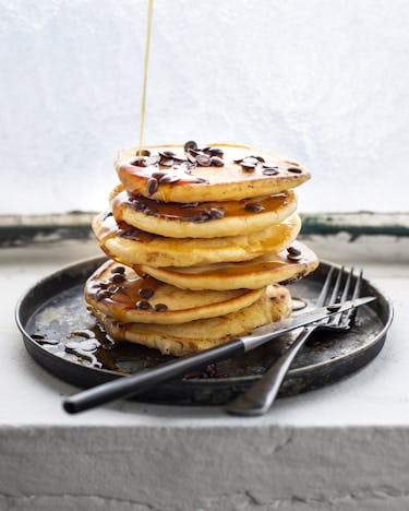 Ein Stapel Pancakes mit Schokolinsenauf einem schwarzen Teller