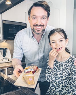 Vater und Tochter präsentieren selbstgemachte Pommestüten in Küche