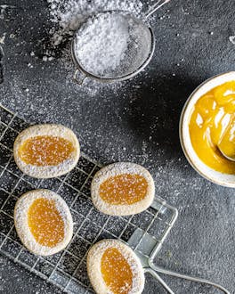 Italienische Zitronenkekse auf dunklem Untergrund mit Lemon Curd und Puderzucker