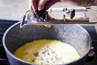 Trüffel werden in Sauce in Kochtopf gehobelt