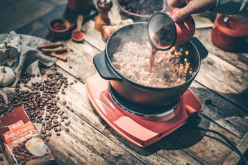 Ein Topf mit Chili steht auf einer Kochplatte und wird mit Kaffee aufgegossen.