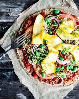 Vegane Blumenkohlpizza auf einem dunklen Holzuntergrund