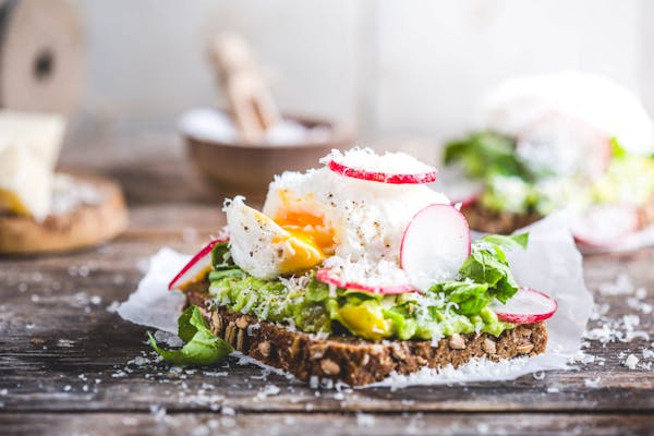 Avocado-Brot mit pochiertem Ei auf Holzuntergrund