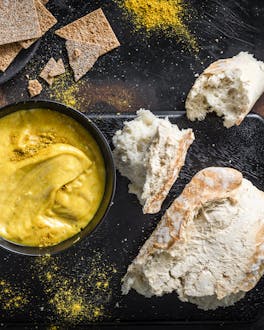 In knalligem Gelb sticht die Currysauce inmitten von Kräckern und Brot hervor.