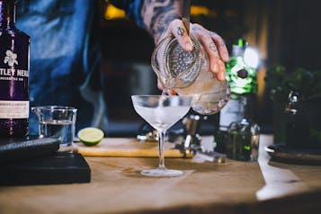 Drink mithilfe des Strainers und des Fine Strainers in die vorgekühlte Cocktailschale füllen.