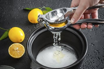 Zitronensaft wird in einen Topf gepresst