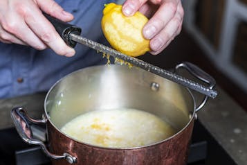 Zitronenabrieb wird ins Risotto in einem Topf gerieben