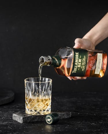Flasche Tullamore Whiskey und ein Tumbler vor schwarzem Hintergrund