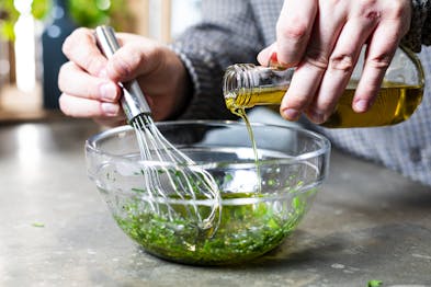 Salatdressing mit Olivenöl in Schüssel anrühren