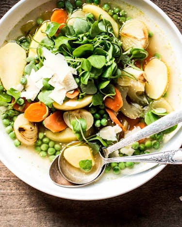 Minestrone gespickt mit Gemüse wie Kartoffeln, Möhren, Erbsen und mehr in einem Suppenteller.