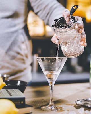 Der Dry Martini wird durch einen Strainer aus dem Rührglas in das Martiniglas gegeben.