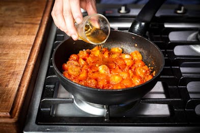 Tomaten und Zwiebeln in einer Pfanne werden mit Likör abgelöscht