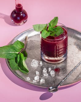 Sour Cocktail mit Rum und Rote Beete, in einem Tumbler auf einem Silbertablett.