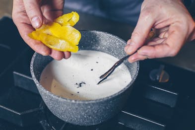 Zitronenschale und Vanilleschote für Crema pasticcera werden in einen Topf Milch gegeben