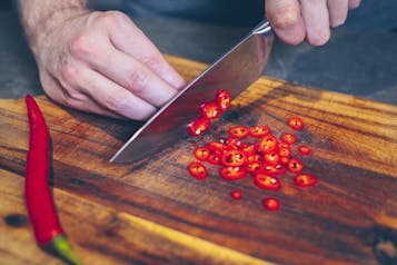 Peperoni werden in Ringe geschnitten auf Holzbrett