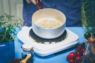 Auf einer Kochplatte steht ein Topf mit Reis.
