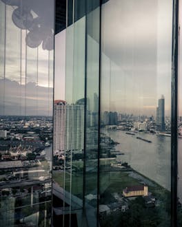 In der Glasfassade eines Hochhaus spiegelt sich die Skyline von Bangkok
