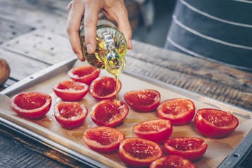 Tomaten auf Backpapier mit Olivenöl beträufeln
