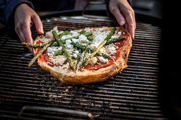 Eine Fladenbrot-Pizza mit grünem Spargel belegt auf einem Grill