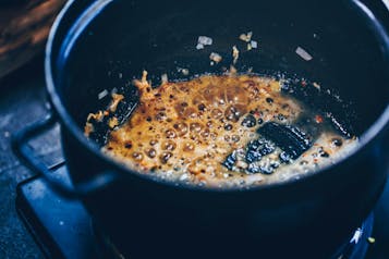 Knoblauch, Schalotte, Ingwer und Chili wird in einem dunklen Topf angeschwitzt