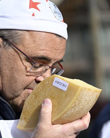 Nahaufnahme von einem Mann, der bei den Swiss Cheese Awards an einem großen Stück Hartkäse riecht