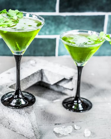 2 Gläser mit dem grünen Drink stehen auf einem hellen Untergrund