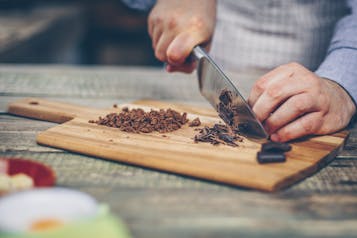 Nougat und Zartbitterschokolade werden auf einem Holzbrett gehackt