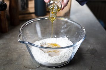 Olivenöl wird in Schüssel mit Zutaten für Teig für Pizzabällchen gegeben