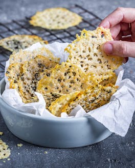Parmesanchips in Schale mit Käse im Hintergrund