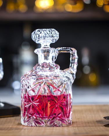 Himbeer-Gin-Infusion in einer Kristallflasche auf einer Bartheke.
