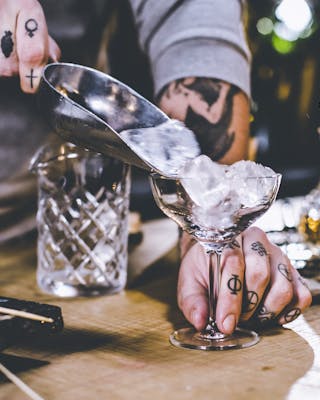 Glas mit Eis kühlen für einen Manhattan Cocktail.