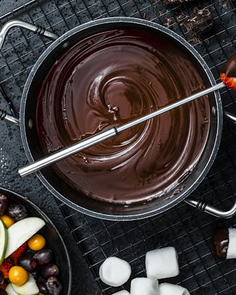 Topf mit geschmolzenem Schokoladen-Fondue und einer Schale mit Früchten